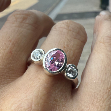 skinny wrists Pink gemstone ring on a hand with a blurred street background