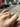 Hand wearing a ring with green gemstones against a blurred background