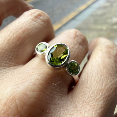 skinny wrists Silver ring with green peridot gemstones on a person's finger