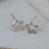 skinny wrists sterling silver open star stud earrings laid on a flat surface.