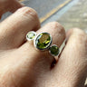 skinny wrists Silver ring with green peridot gemstones on a person's finger