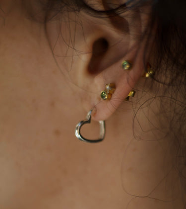 Close-up of an ear with heart-shaped earrings on a neutral background
